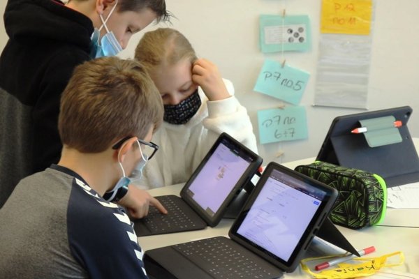 Foto: Schülerin und Schüler arbeiten an zwei iPads
