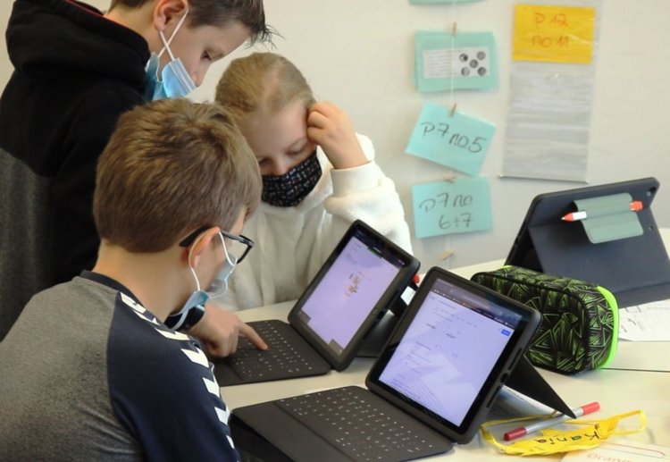 Foto: Schülerin und Schüler arbeiten an zwei iPads