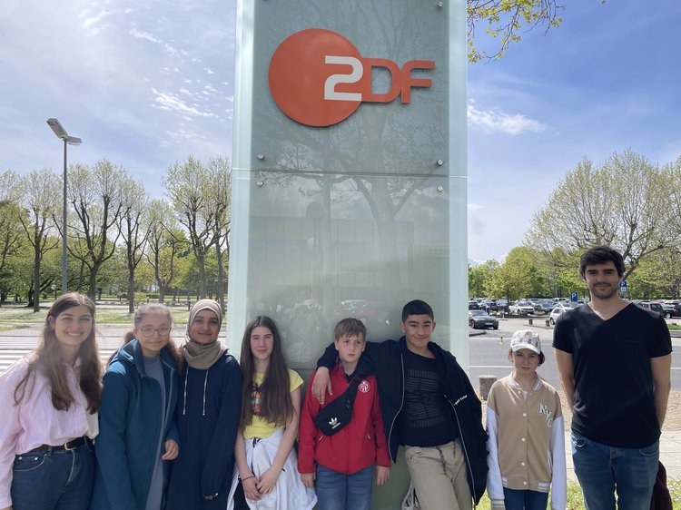 2 Lehrkräfte stehen mit 6 SchülerInnen vor dem Schild des ZDF