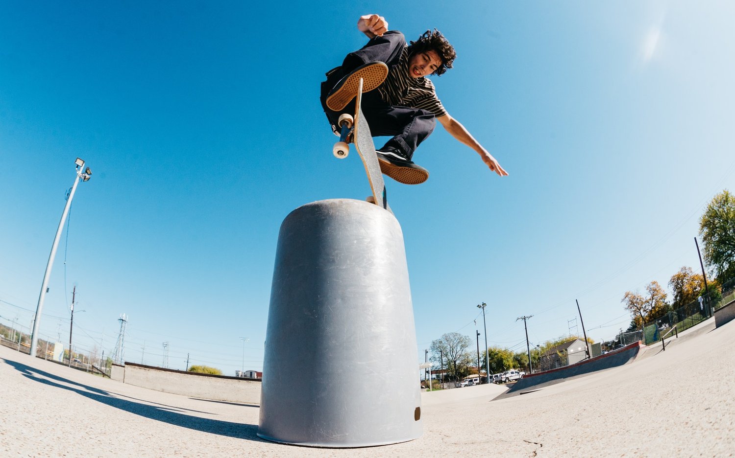 Foto: Jugendlicher mit Skateboard im Sprung an einem künstlichen Hindernis.