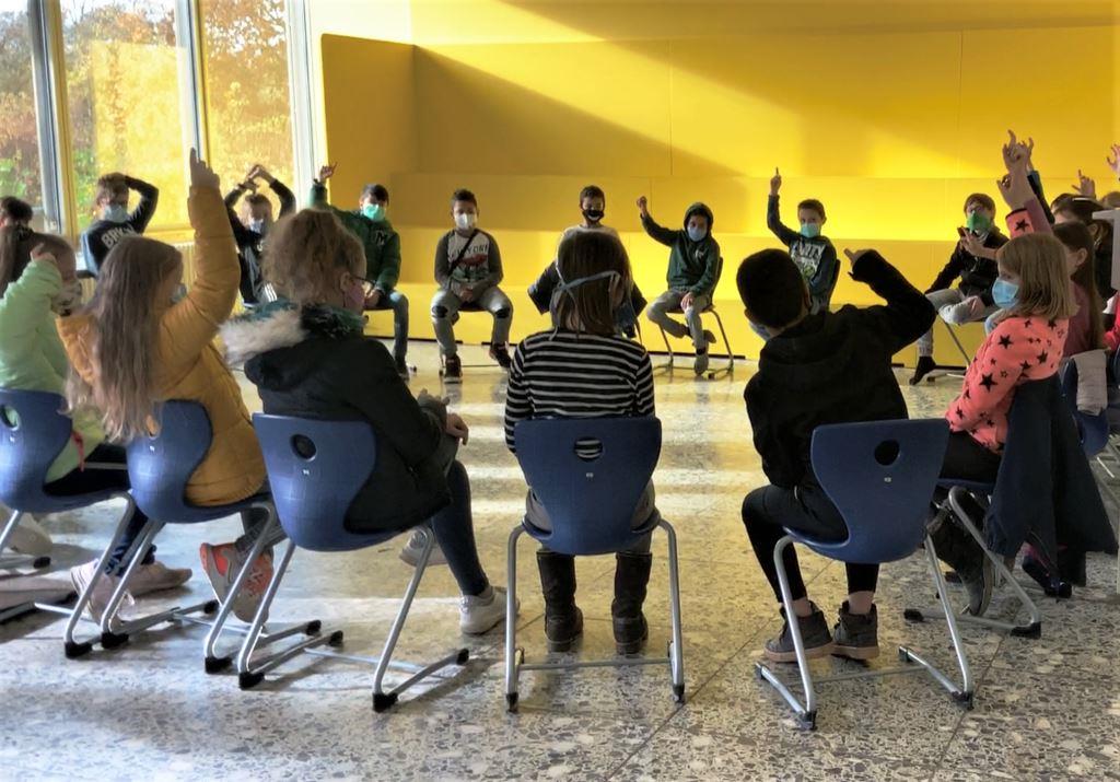 Foto: Schülerinnen und Schüler sitzen im Kreis und stimmen über etwas ab
